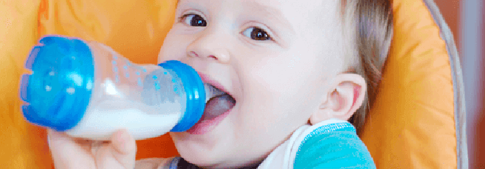 Bebé de un año tomando leche de crecimiento en biberón