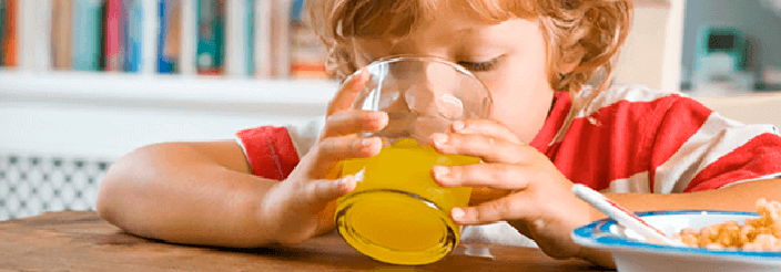 Niña bebiendo un refresco de naranja