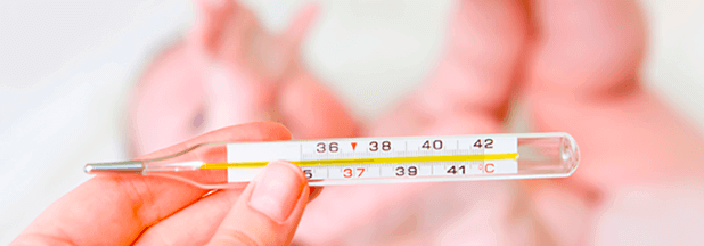 Madre midiendo la temperatura de su bebé por si tiene fiebre