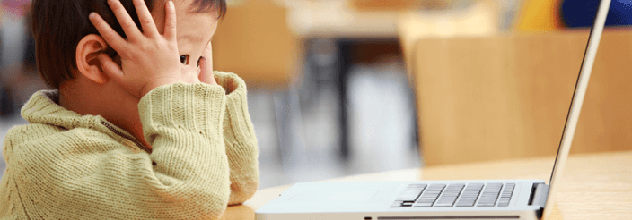 Niño con dolor de cabeza frente a un ordenador