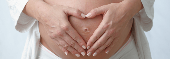 Mujer embarazada tocándose el vientre con las dos manos