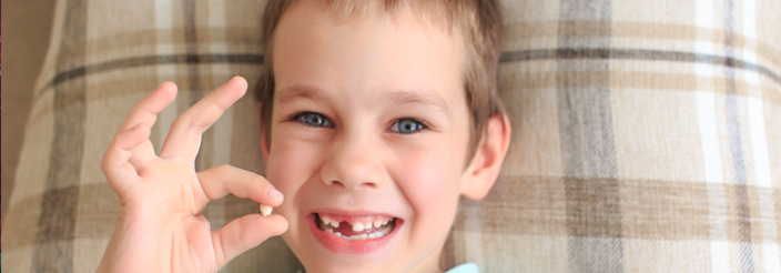 Niño mostrando el primer diente de leche que se le ha caído