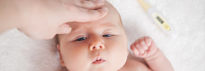 Adulto tocando la frente de su bebé para medir la fiebre