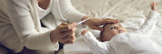 Madre midiendo la fiebre a su bebé con un termómetro