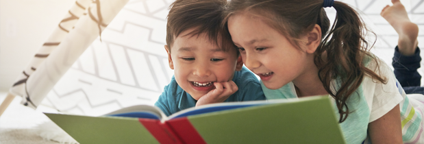 Dos hermanos leyendo en voz alta un cuento infantil