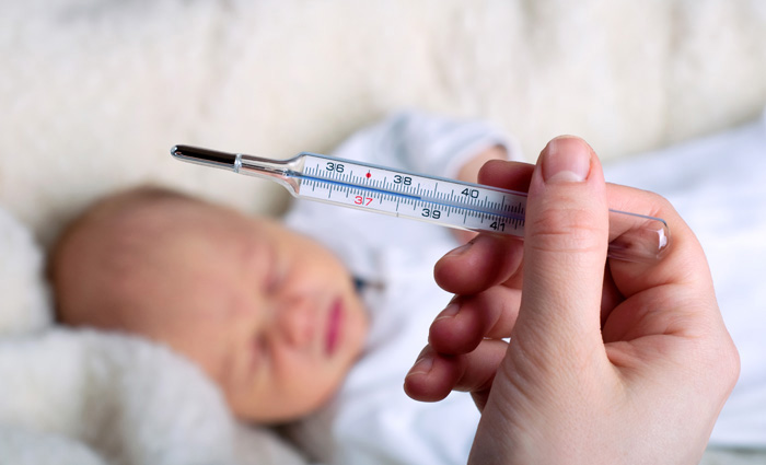 Adulto midiendo la fiebre de su bebé