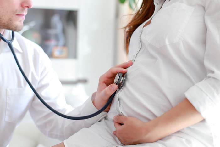 La mujer embarazada escucha los latidos del corazón y los movimientos del  bebé con un estetoscopio o un fetoscopio o un Pinard Horn. Salud fetal  prenatal, ansiedad, concepto del miedo. Fotografías de