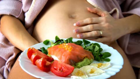 Mujer comiendo pescado crudo y riesgo de anisakis en embarazo