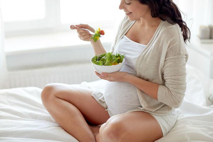 Mujer embarazada comiendo ensalada