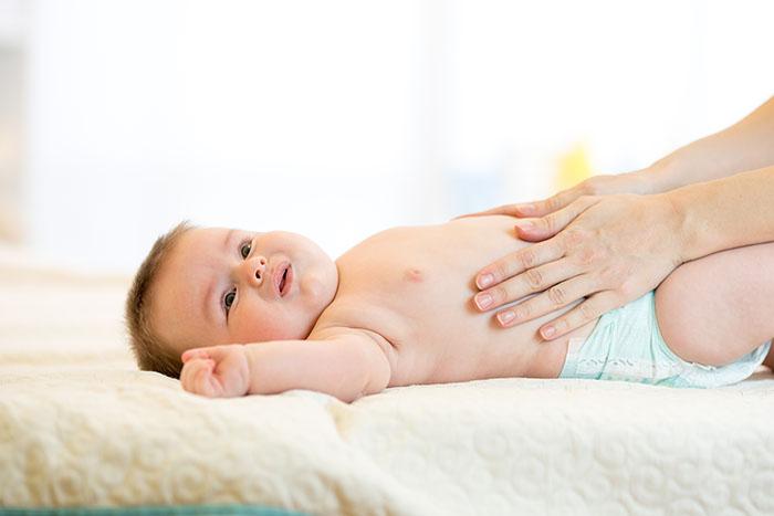 Bebé recibiendo un masaje en el abdomen para la disquecia