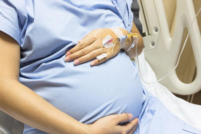 Mujer embarazada en el hospital con goteros en la mano