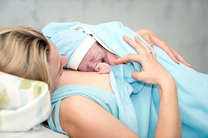Mujer con su bebé recién nacido en la camilla del hospital tras el parto