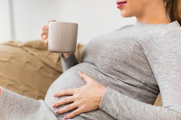 Mujer embarazada tomando una infusión para quitarse el frío