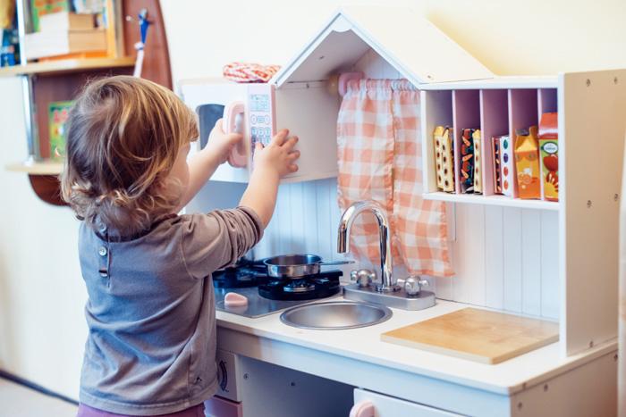 Niño de 2 años jugando con una cocina de juguete