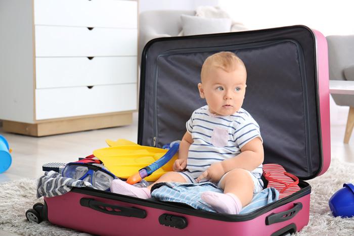 Bebé sobre una maleta antes de un viaje