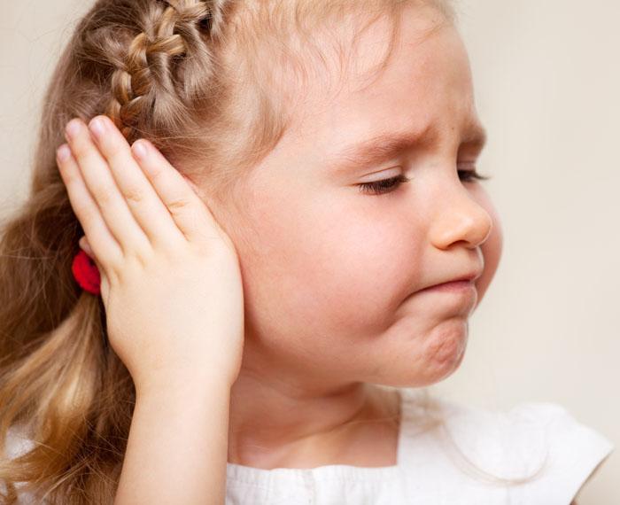 Niña tocándose la oreja por dolor de oído