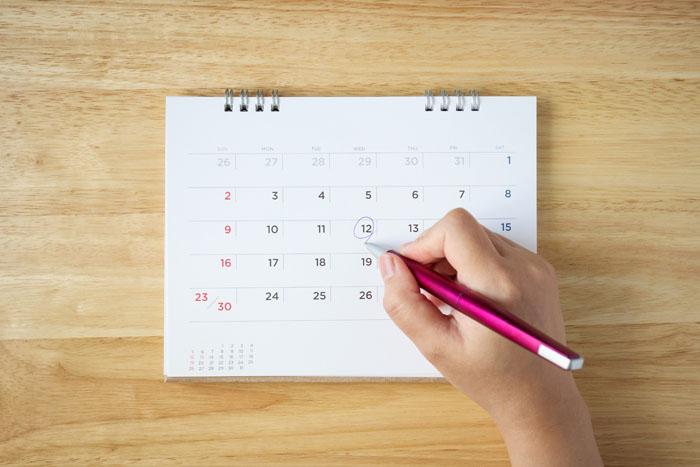 Mano de mujer anotando el día de ovulación en un calendario