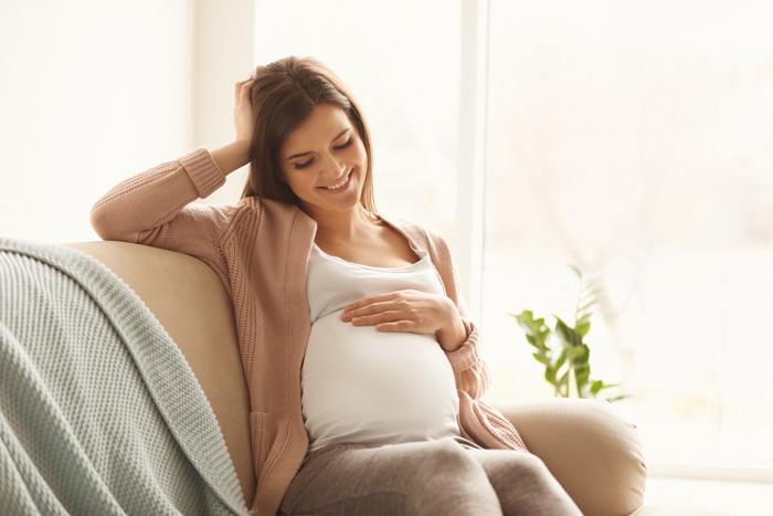 Mujer embarazada en el sofá notando a su bebé