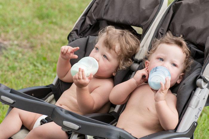 Gemelos en un cochecito tomando biberón