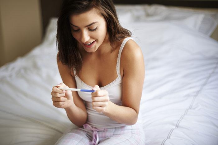 Mujer mirando un test positivo de embarazo