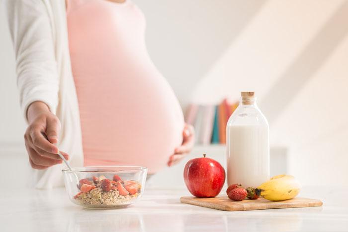 Mujer embarazada preparando un desayuno saludable