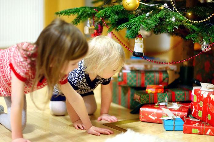 Niñas buscando sus regalos de Navidad bajo el árbol