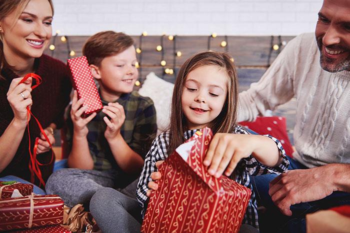 Niña abriendo un regalo de Reyes con su familia