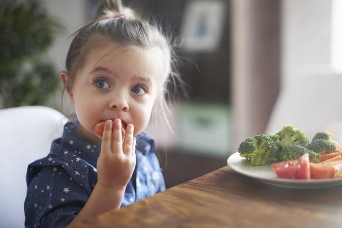 Niña comiendo un plato de verdura