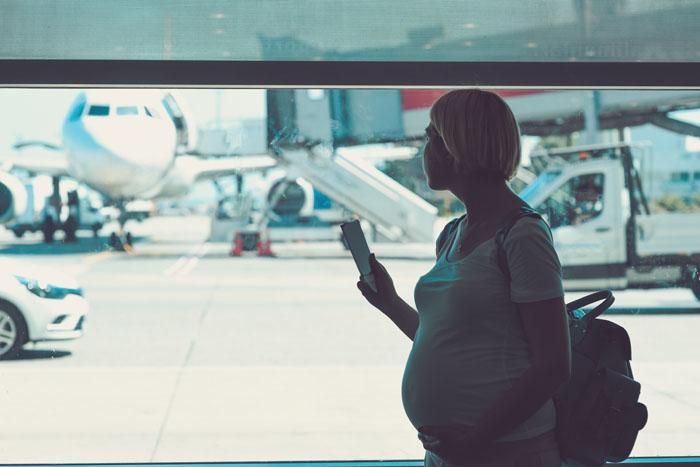Mujer embarazada en un aeropuerto antes de hacer un viaje
