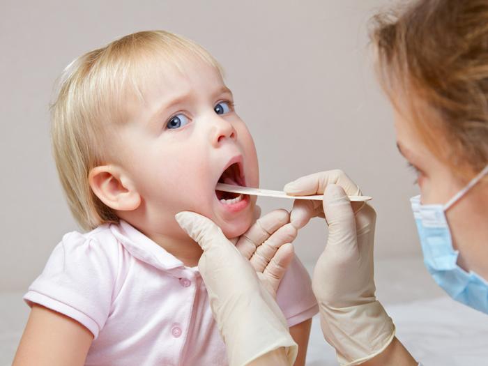 Médico examinando las cuerdas vocales de una niña