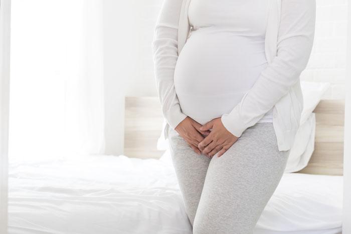 Mujer embarazada con candidiasis poniendo las manos en la zona genital
