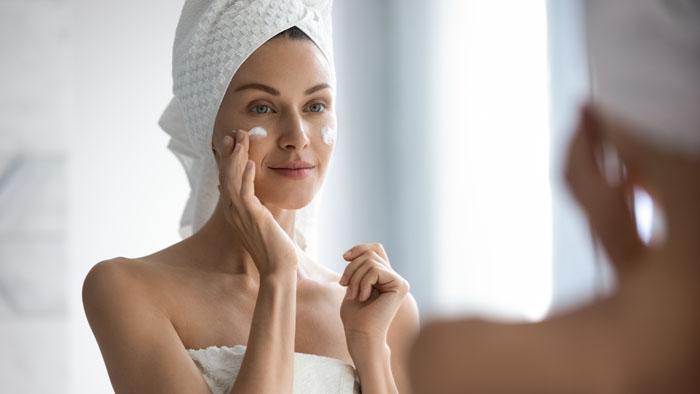 Mujer poniéndose crema en la cara ante el espejo