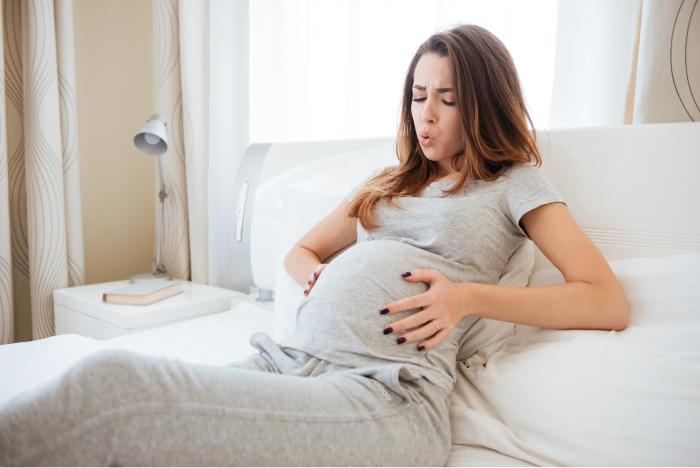 Mujer embarazada sufriendo una contracción en su casa