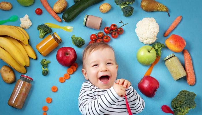 ​​​Bebé rodeado de alimentos saludables como fruta y verduras