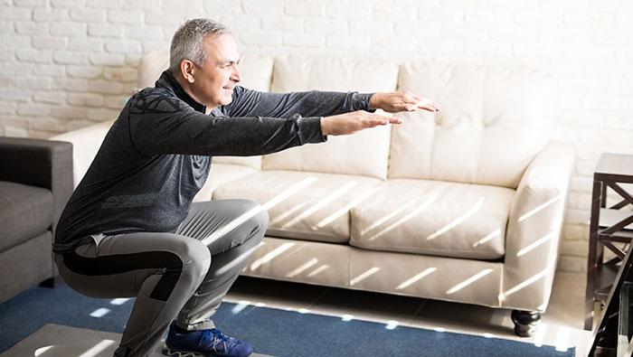 Hombre mayor haciendo ejercicio en el salón de su casa