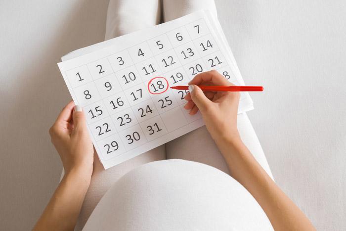 Mujer embarazada anotando la fecha de parto en el calendario