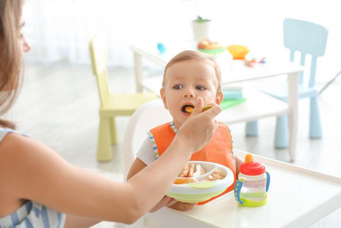 Madre dando de comer a su hijo en la trona