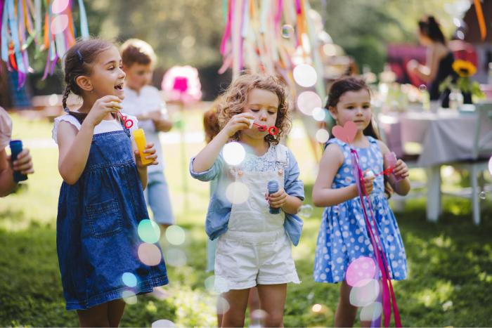 Niñas haciendo burbujas en una fiesta de cumpleaños al aire libre