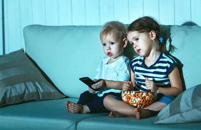 Niño y niña viendo una película infantil en su casa