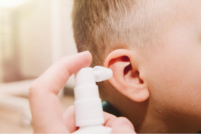 Padre limpiando los oídos de su bebé con un spray ótico