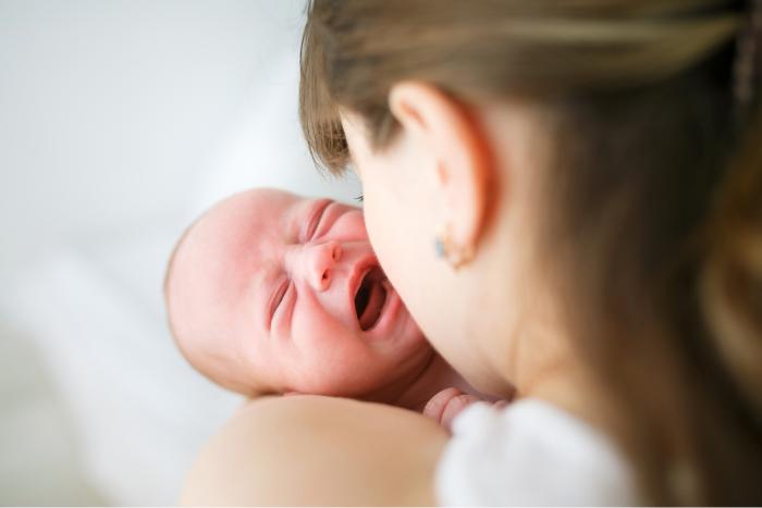  Madre sosteniendo en brazos a su bebé que llora por cólicos del lactante