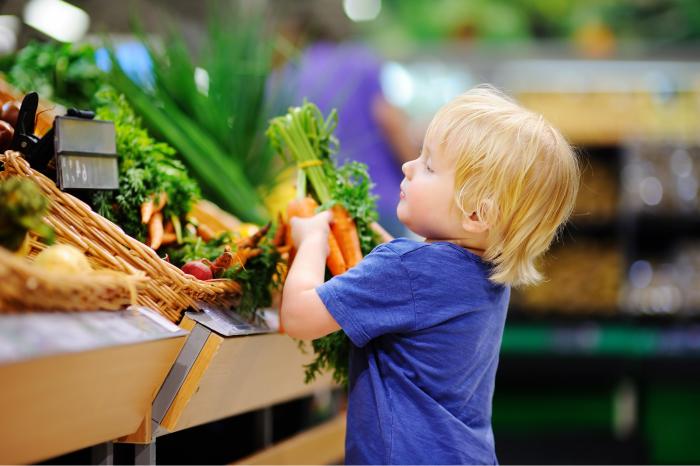 Niño cogiendo verdura en el supermercado