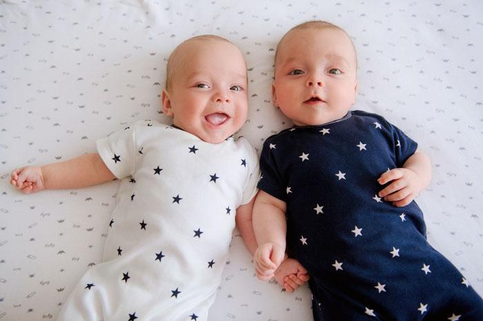 Bebés gemelos tumbados en la cama y sonriendo