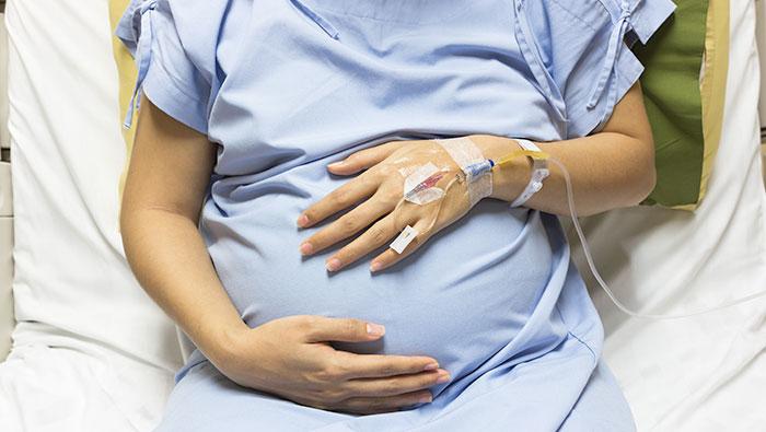 Mujer embarazada en una cama de hospital con suero fisiológico antes del parto