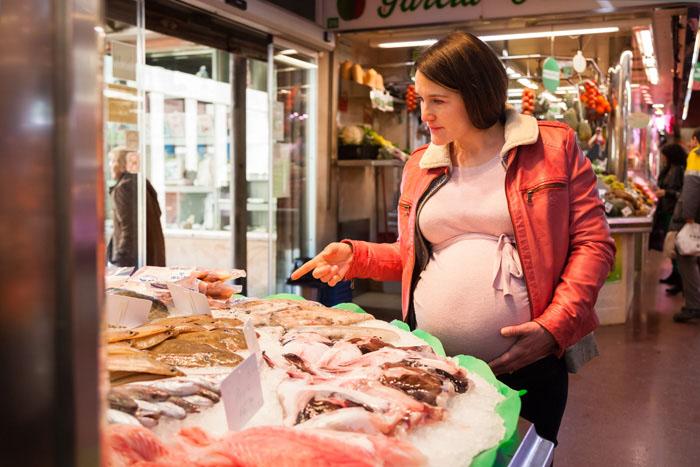 Mujer embarazada comprando pescado rico en vitamina D