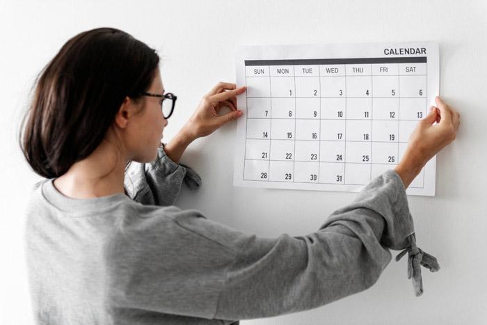 Mujer fijando un calendario en la pared