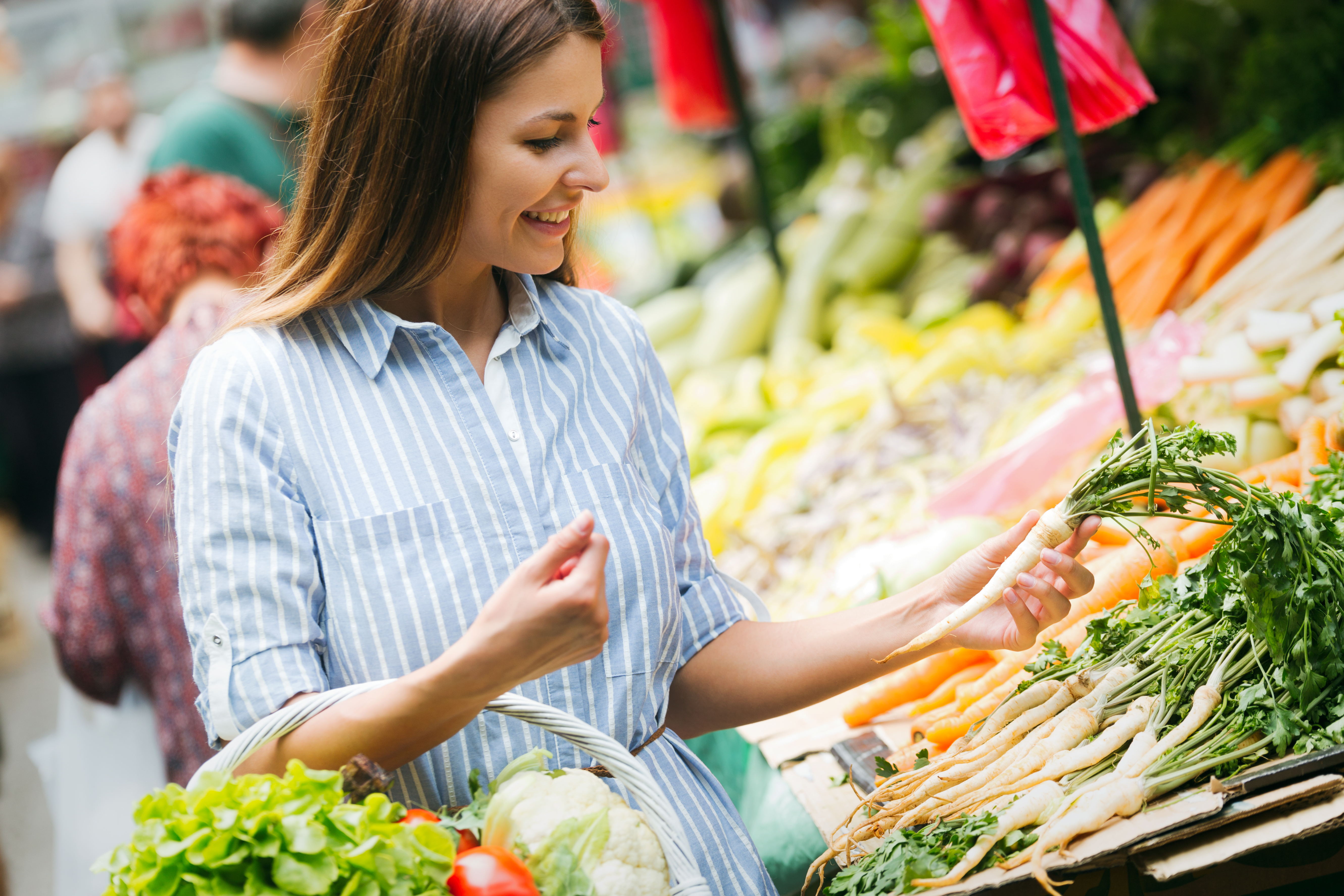 Mujer en edad fértil comprando verduras en el mercado