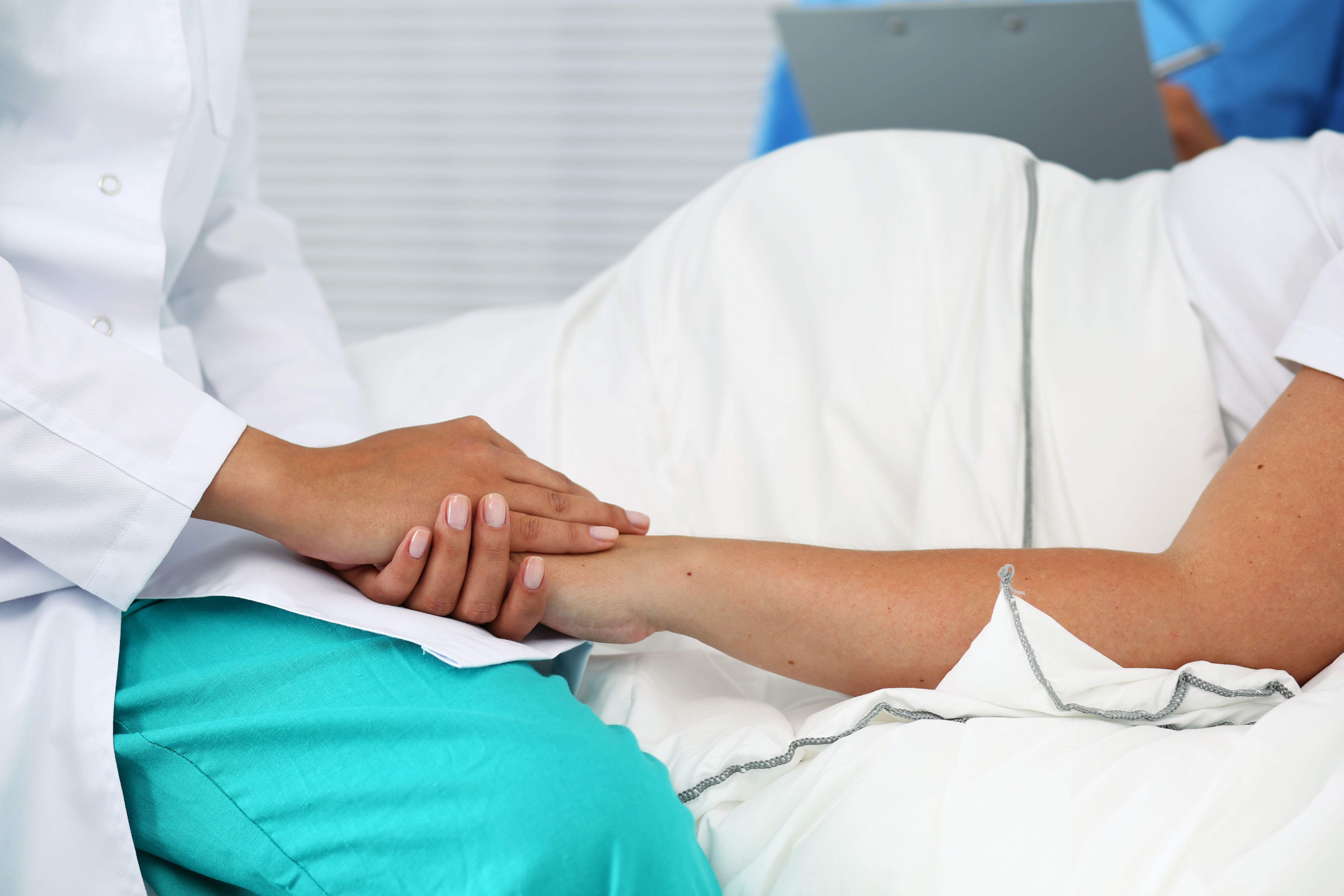 Mujer embarazada en una camilla de hospital mientras una doctora le coge la mano