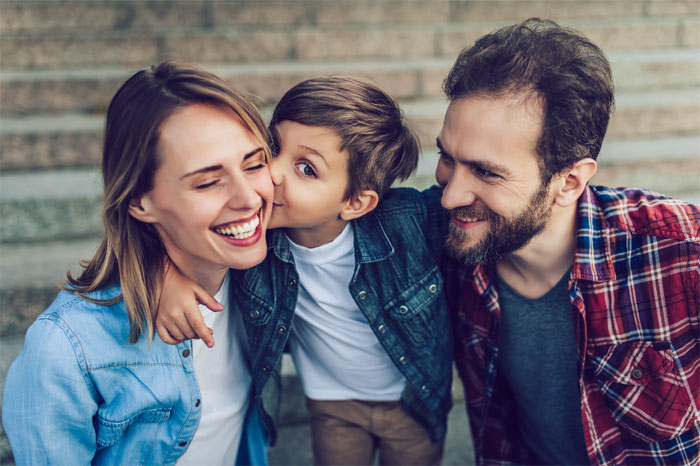 Padre y madre con su hijo que besa a la madre