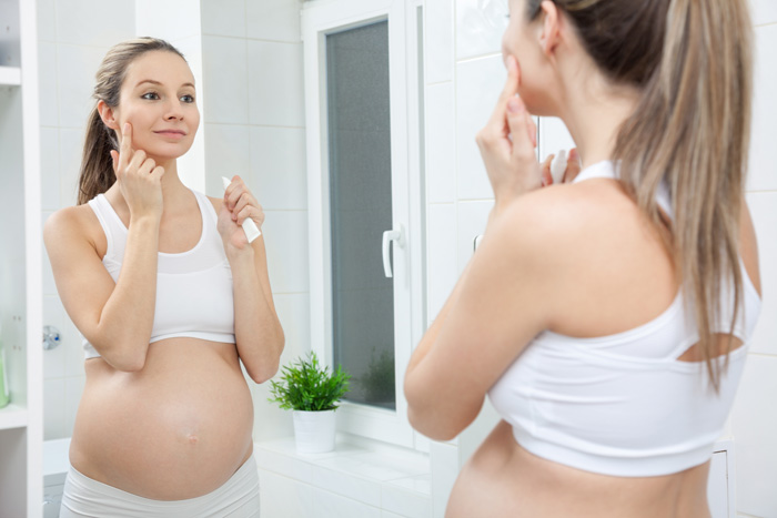 Mujer embarazada poniéndose crema en la cara